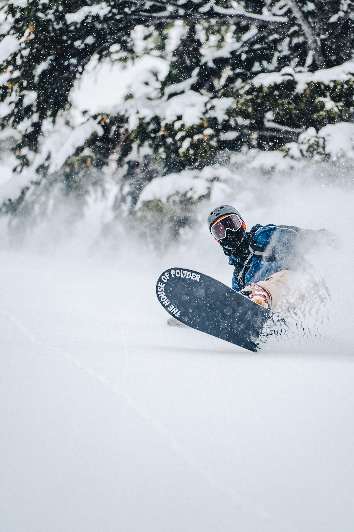 A snowboarder riding through powder