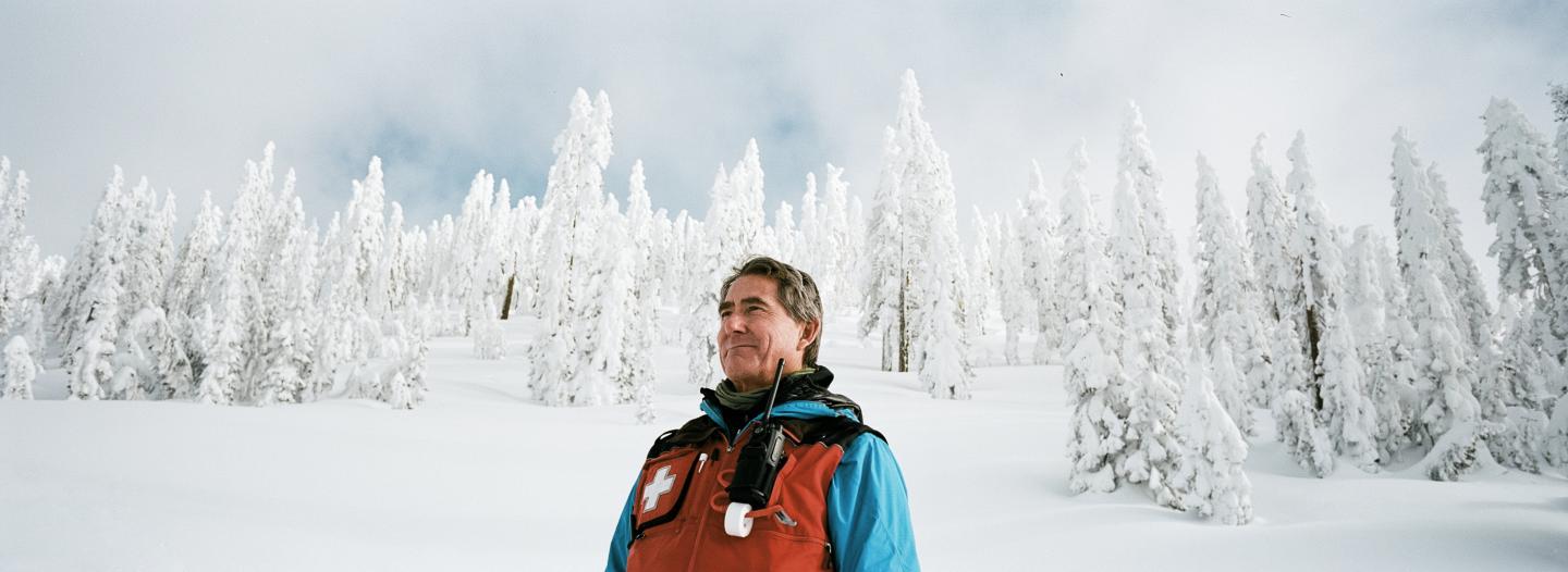 A portrait of a ski patrol employee on a mountain