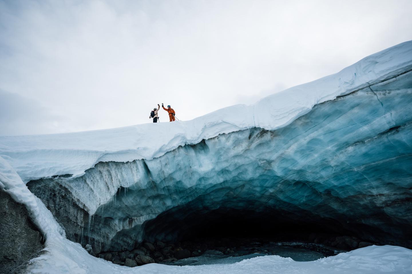 two skiers high-fiving over a mountain pass