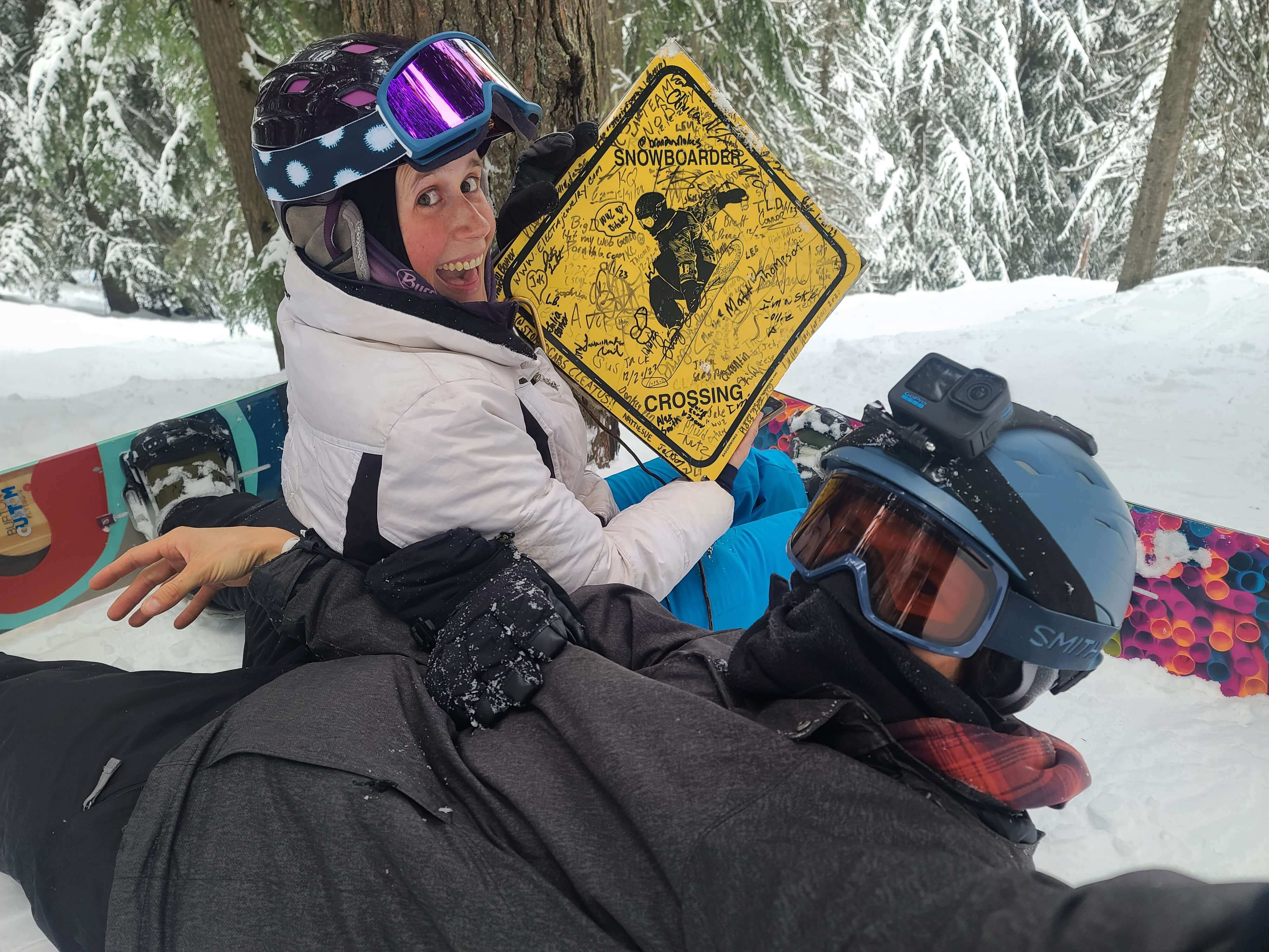 Andrea and Brian with a snowboarder crossing sign at 49 Degrees North
