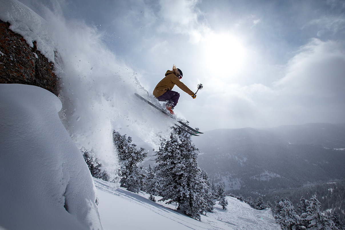 skier jumping off a rock cliff into powder at Beaver Mountain, Utah