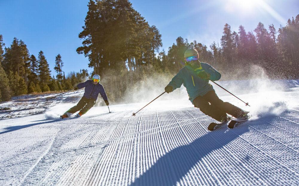 two skiers riding groomers