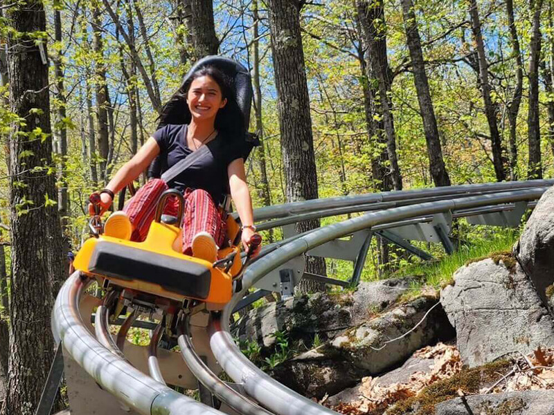 woman riding a mountain coaster through the woods at Spirit Mountain Duluth, an Indy Pass partner